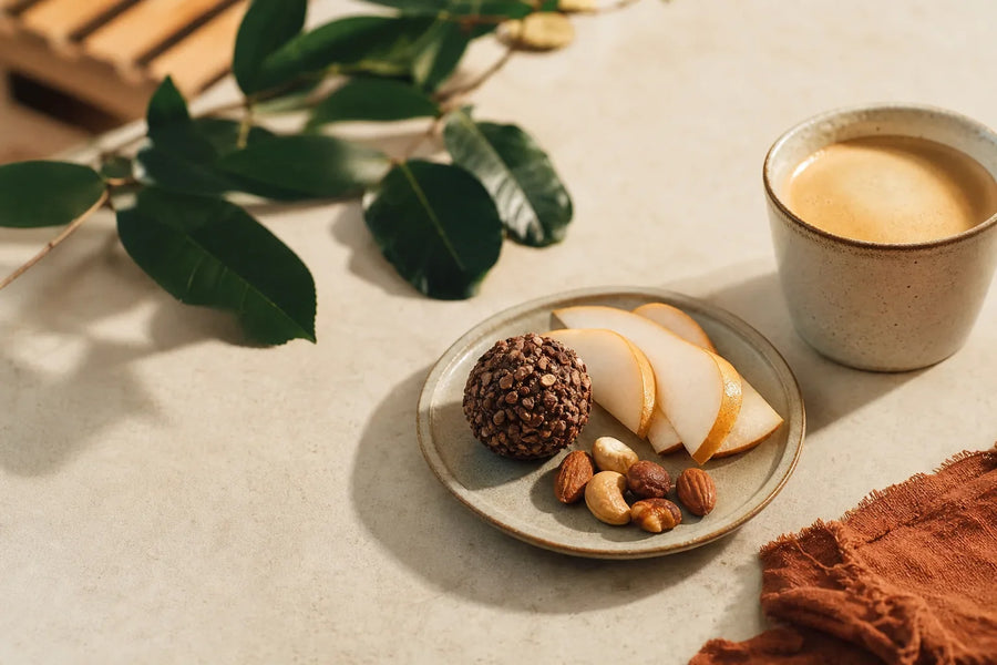 Pequeno snack de cacau e castanhas com pera e café.
